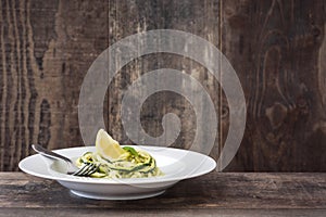 Zucchini noodles with pesto sauce on wooden table