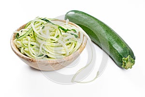 Zucchini noodles in a rustic wooden bowl isolated