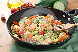 Zucchini noodles sauteed with cherry tomato and prawns in a pan