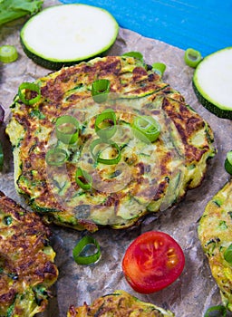 Zucchini pancakes with chives on a wooden table