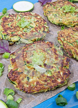 Zucchini pancakes with chives on a wooden table