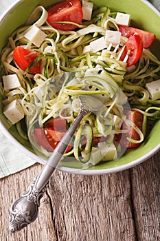 Zucchini pasta with cheese and tomato close up in a bowl. vertic