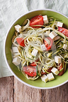 Zucchini pasta with feta cheese and tomatoes closeup vertical to