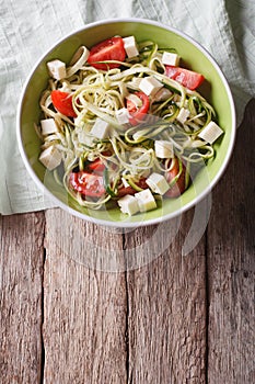 Zucchini pasta with feta cheese and tomatoes vertical top view