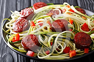 Zucchini pasta with fresh pepper and fried sausages close-up. ho