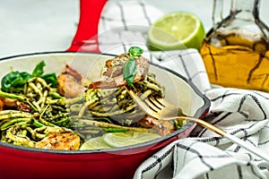 Zucchini pasta with pesto sauce and grilled shrimp in pan. Food recipe background. Close up