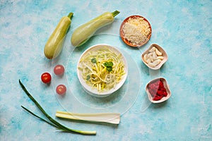 Zucchini raw vegan pasta with cherry tomatoes on plate. On blue background. Vegetarian healthy food