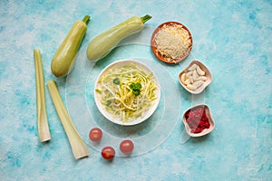 Zucchini raw vegan pasta with cherry tomatoes on plate. On blue background. Vegetarian healthy food