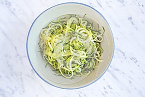 Zucchini spaghetti or noodles & x28;zoodles& x29; in a bowl with marble ba