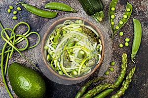 Zucchini spaghetti or noodles zoodles bowl with green veggies and garlic scape pesto. Top view, overhead.