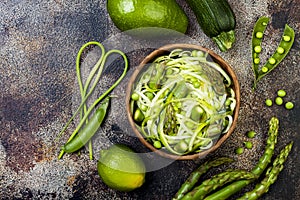 Zucchini spaghetti or noodles zoodles bowl with green veggies and garlic scape pesto. Top view, overhead.