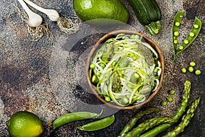 Zucchini spaghetti or noodles zoodles bowl with green veggies. Top view, overhead, copy space.