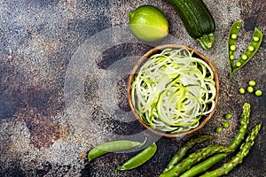 Zucchini spaghetti or noodles zoodles bowl with green veggies. Top view, overhead, copy space.