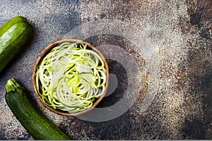 Zucchini spaghetti or noodles zoodles bowl with green veggies. Top view, overhead, copy space.