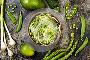 Zucchini spaghetti or noodles zoodles bowl with green veggies. Top view, overhead, copy space.