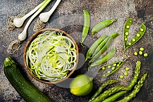 Zucchini spaghetti or noodles zoodles bowl with green veggies. Top view, overhead, copy space.