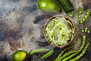 Zucchini spaghetti or noodles zoodles bowl with green veggies. Top view, overhead, copy space.