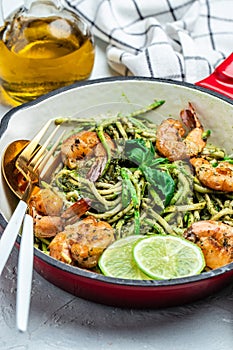 Zucchini spaghetti with pesto sauce and grilled shrimp skewers in pan. keto low carb diet. banner, menu, recipe place for text,