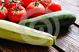 Zucchini and tomato on wood background closeup