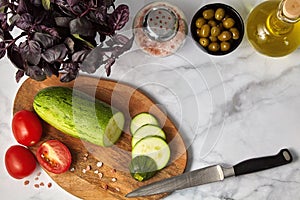 Zucchini tomatoes olives basil oil and salt on a wooden board on a light table