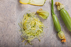 Zucchini vegetable noodles - green zoodles or courgette spaghetti on plate over gray background. Clean eating, raw vegetarian food