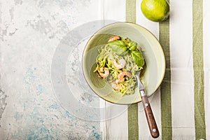 Zucchini Vegetable noodles - green zoodles or courgette spaghetti  with shrimps on plate over gray background. Clean eating, raw