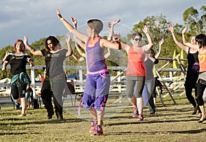 Zumba dancing instructor with smiling dancing people