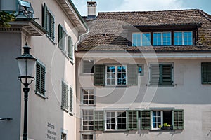 Zurich architecture. The facade of the house, windows with green shutters, brown tile roof.