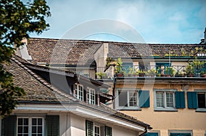 Zurich architecture. The facade of the house, windows with green shutters, brown tile roof. Terrace decorated with