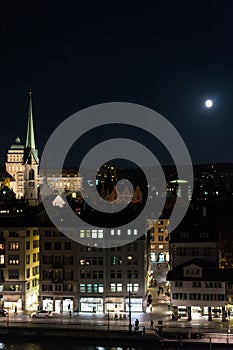 Zurich city by night with full moon shinging and light on buildings