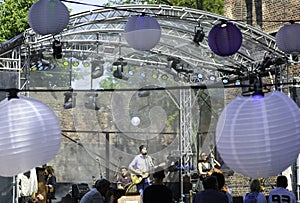 people listening to an outdoor concert. Performance of a music band on a stage with lights outdoor. Outdoor