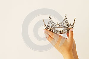 ×—Woman& x27;s hand holding a crown for show victory or winning first place. White background. Copy space. .