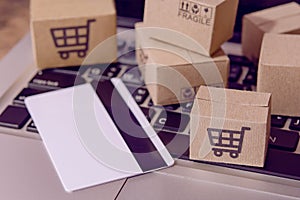 â€¨Shopping online. Credit card and cardboard box with a shopping cart logo on laptop keyboard. Shopping service on The online web