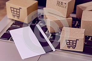â€¨Shopping online. Credit card and cardboard box with a shopping cart logo on laptop keyboard. Shopping service on The online web