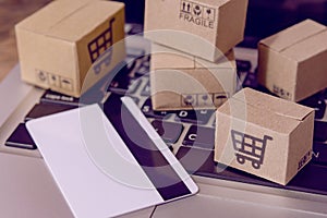 â€¨Shopping online. Credit card and cardboard box with a shopping cart logo on laptop keyboard. Shopping service on The online web