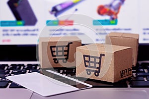 â€¨Shopping online. Credit card and cardboard box with a shopping cart logo on laptop keyboard. Shopping service on The online web