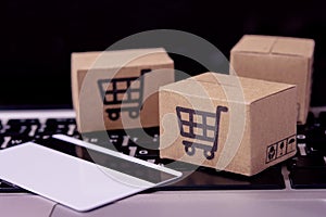 â€¨Shopping online. Credit card and cardboard box with a shopping cart logo on laptop keyboard. Shopping service on The online web