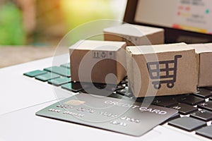 â€¨Shopping online. Credit card and cardboard box with a shopping cart logo on laptop keyboard. Shopping service on The online web