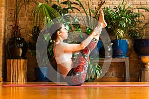 â€ŽYoung woman practicing yoga in studio