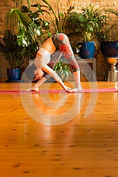 â€ŽYoung woman practicing yoga in studio