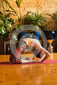 â€ŽYoung woman practicing yoga in studio