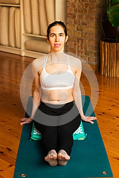 â€ŽYoung woman practicing yoga in studio