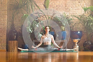 â€ŽYoung woman practicing yoga in studio. Sitting on green carpet