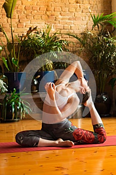 â€ŽYoung woman practicing yoga in studio. Sitting on red mat