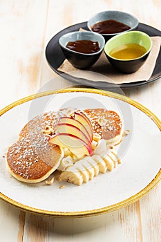 Î’reakfast concept. Pancakes with fruits and syrup on wooden background