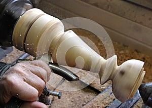 Ðœan grinds a wooden candlestick on a lathe