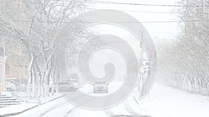 Ð’lizzard, mist and snowfall in city, cars on sleet road, poor visibility, winter bad weather