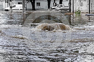 Ð’riving car on flooded road during flood caused by torrential rains. Cars float on water, flooding streets. Splash on car.