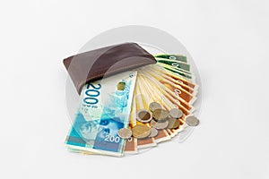 Ð’rown leather wallet and stack of banknotes and several coins of new Israeli shekels on white background