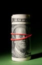 100 Dollar roll tightened with red rubber band. Royalty Free Stock Photo